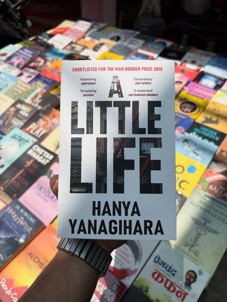 A Little Life by Hanya Yanagihara held over bustling book street table